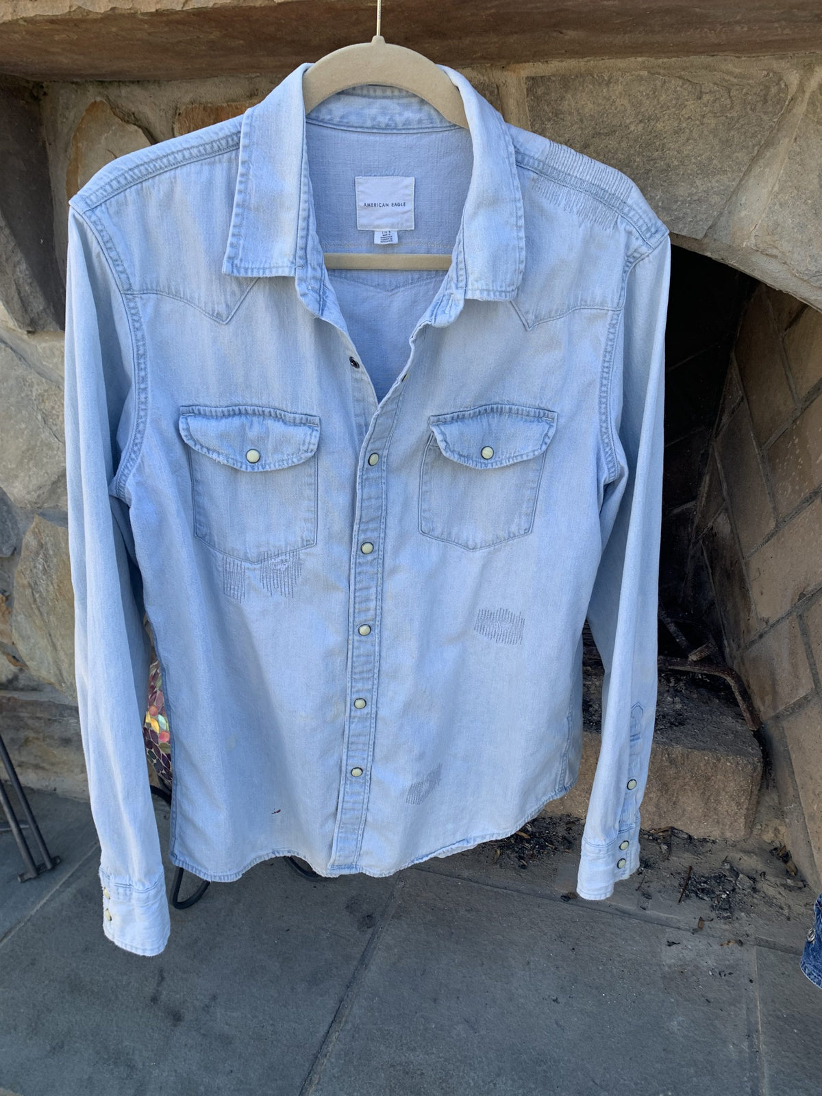 a blue jean shirt hanging on a clothes rack.