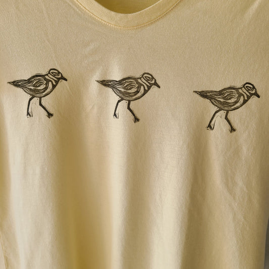 three birds on a yellow shirt with black ink.
