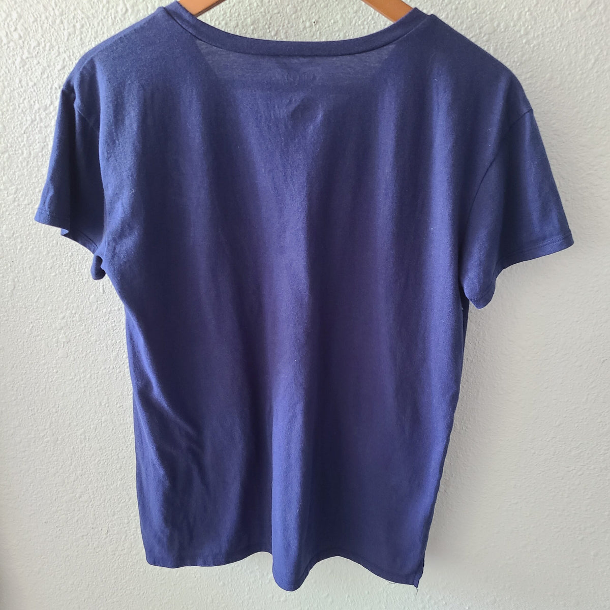 a blue t - shirt hanging on a hanger.