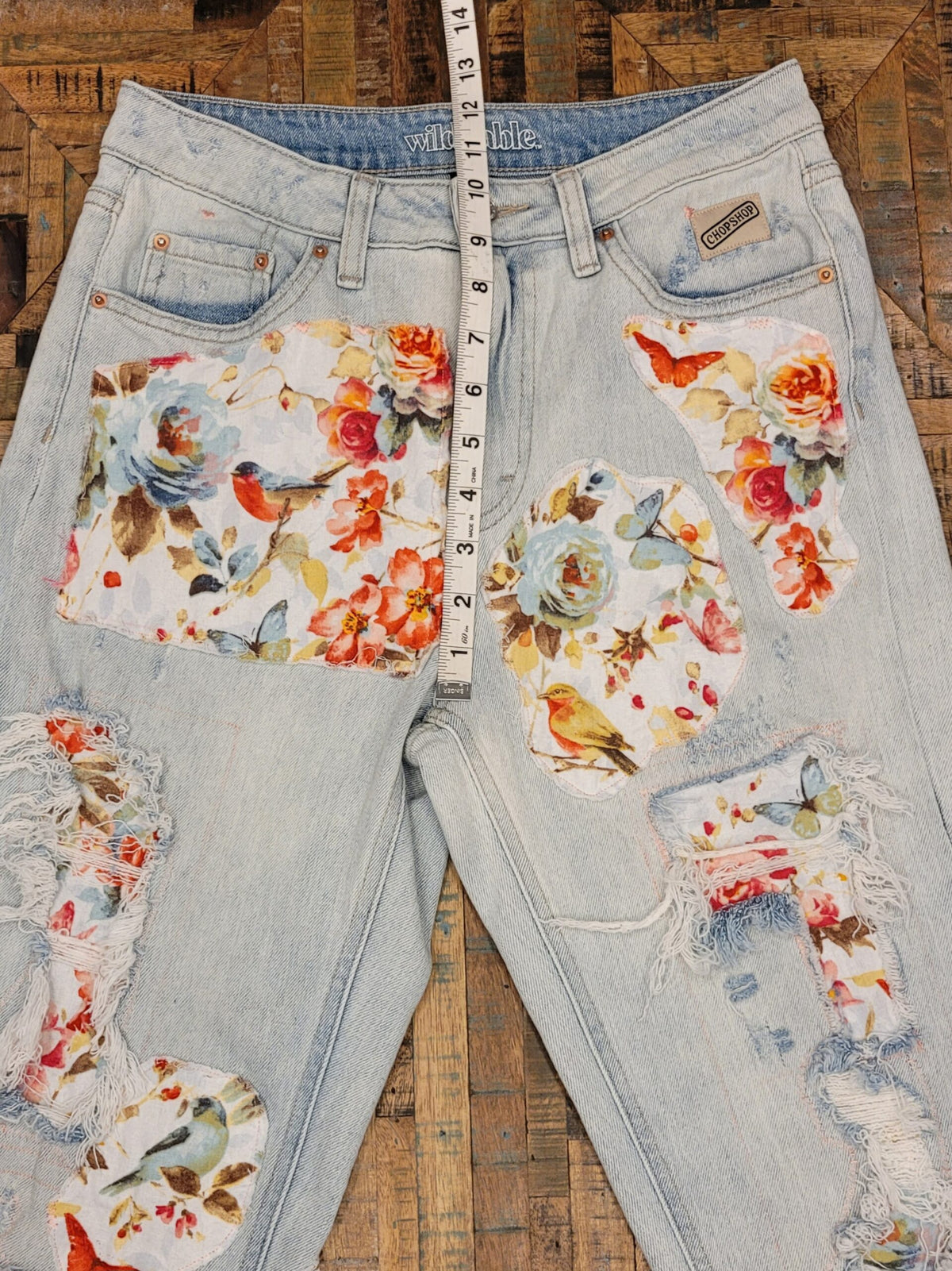 a pair of ripped jeans with flowers on them.