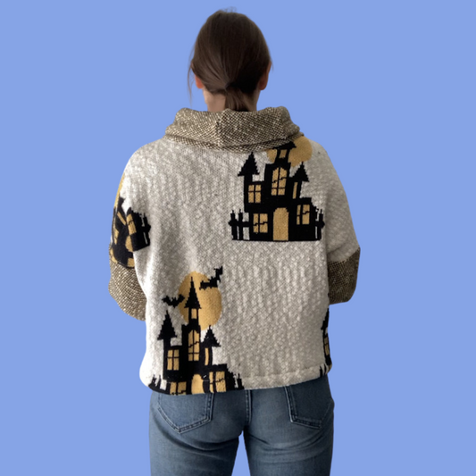 The back of a woman wearing a halloween sweater with a castle on it.