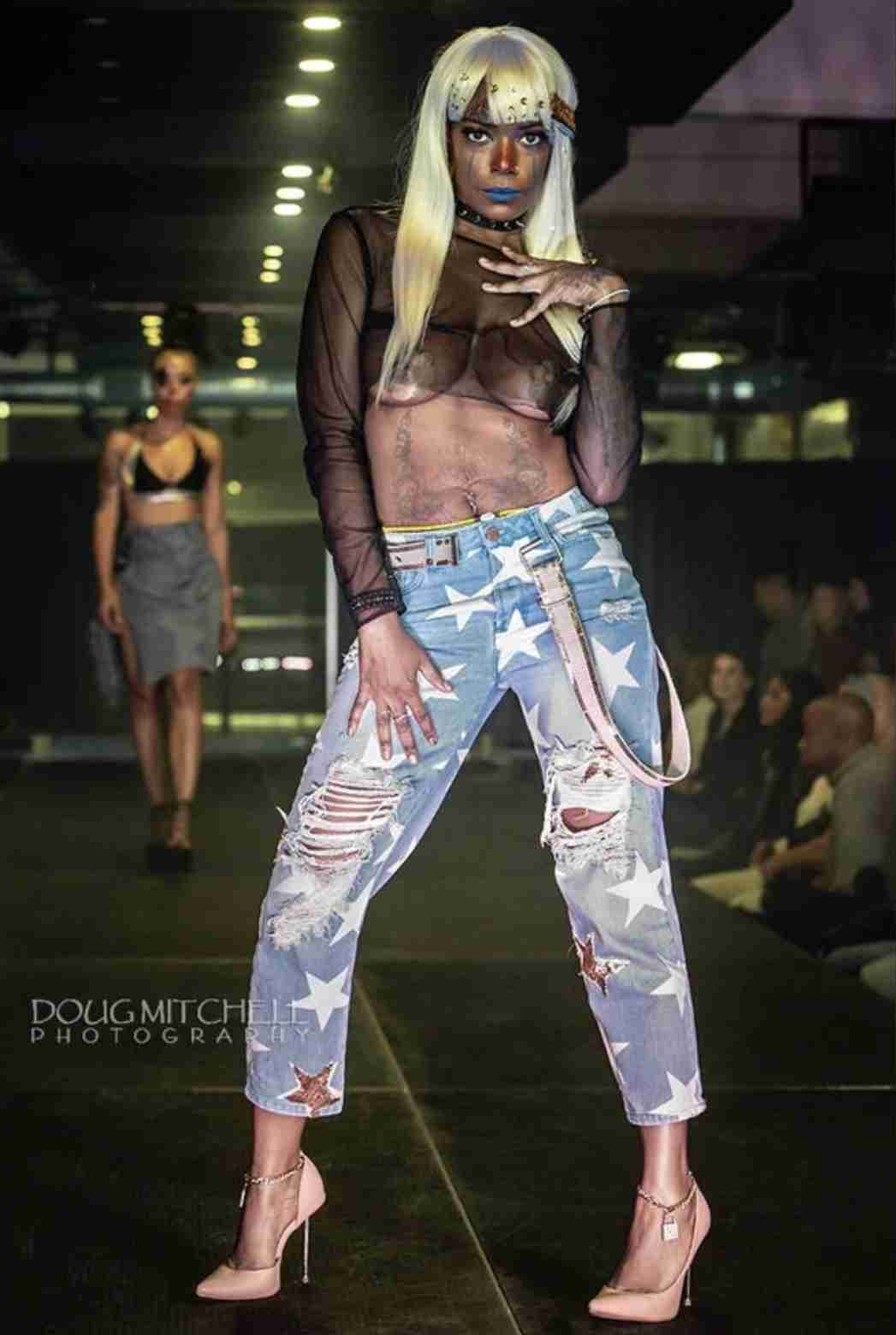 a woman with white hair and makeup on a runway.