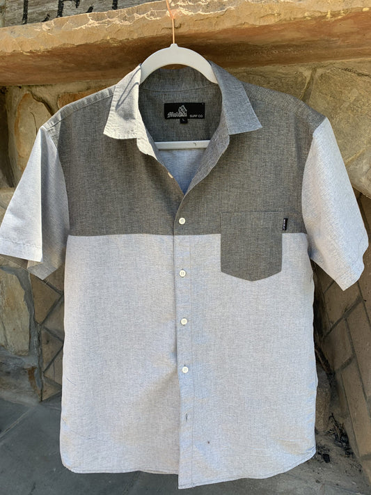 a gray and white shirt hanging on a stone wall.
