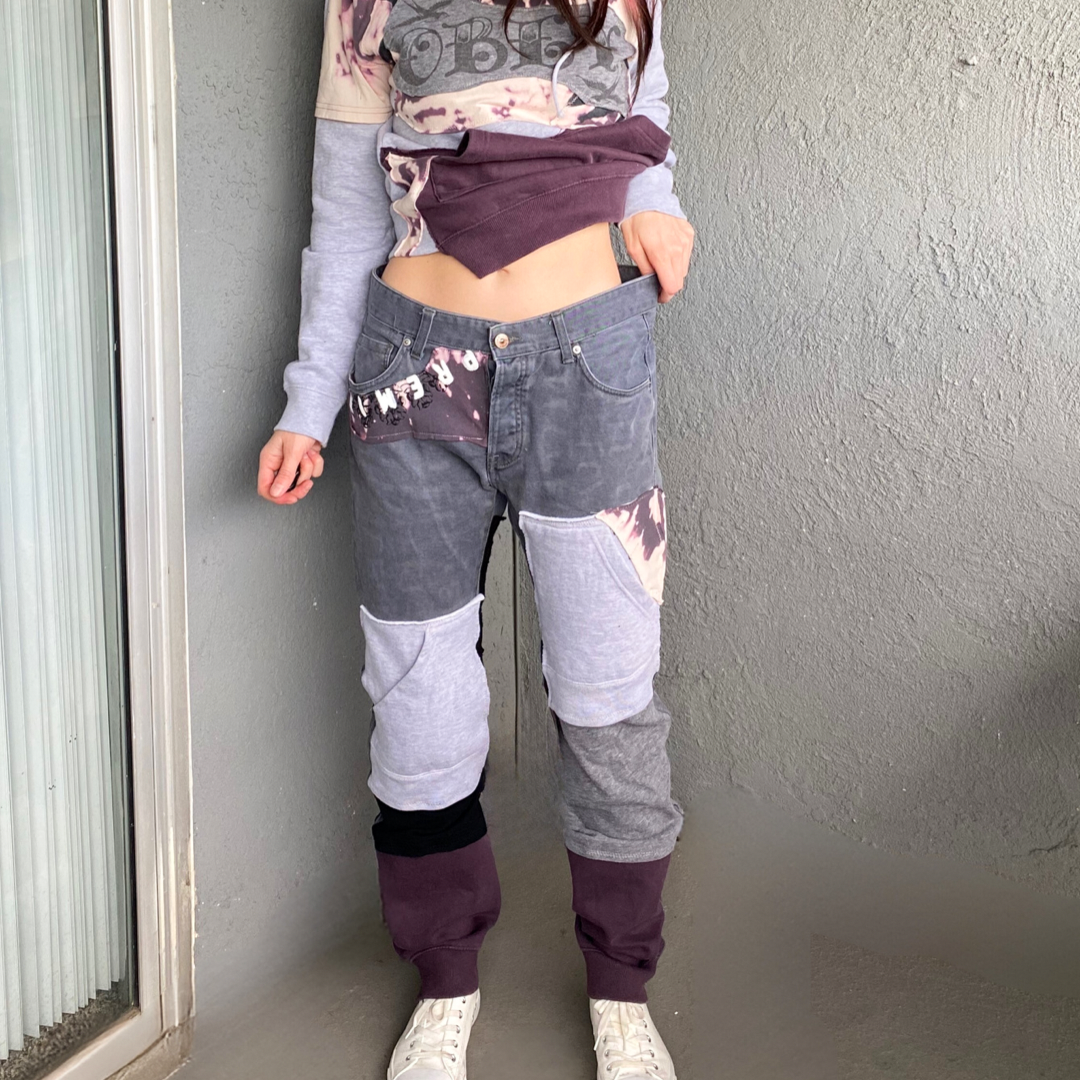 A woman is standing next to a wall wearing a sweater and pants.