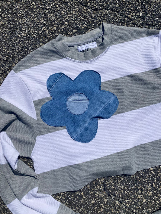 a striped shirt with a blue flower on it.