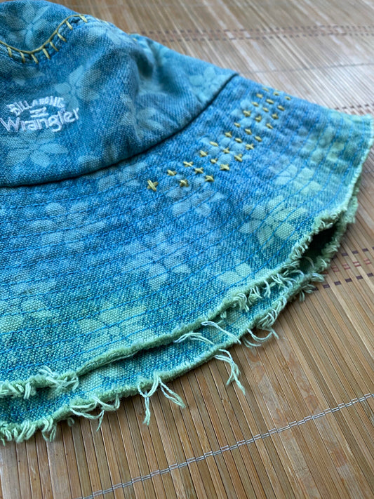 A blue denim bucket hat on a bamboo mat.