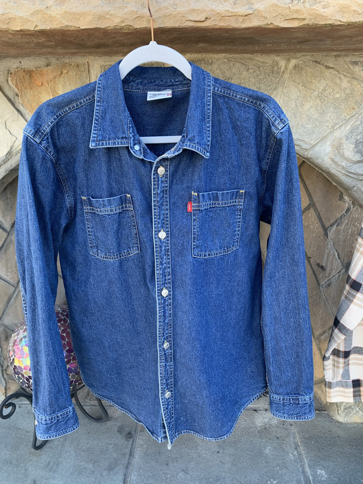 a blue jean shirt hanging on a clothes line.