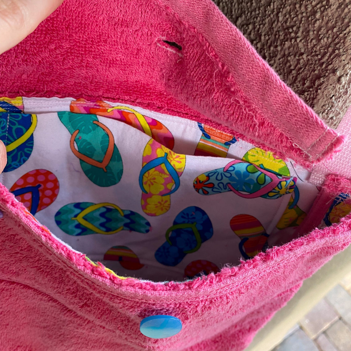 A person is holding a 1of1 pink terrycloth purse with a pair of scissors in it.