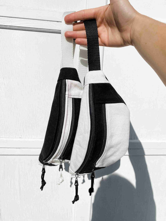 a hand holding a white and black purse.