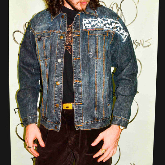 a man with long hair wearing a jean jacket.