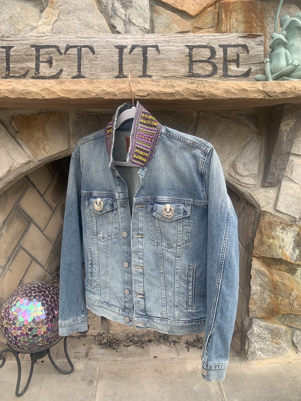 a denim jacket hanging on a brick wall.