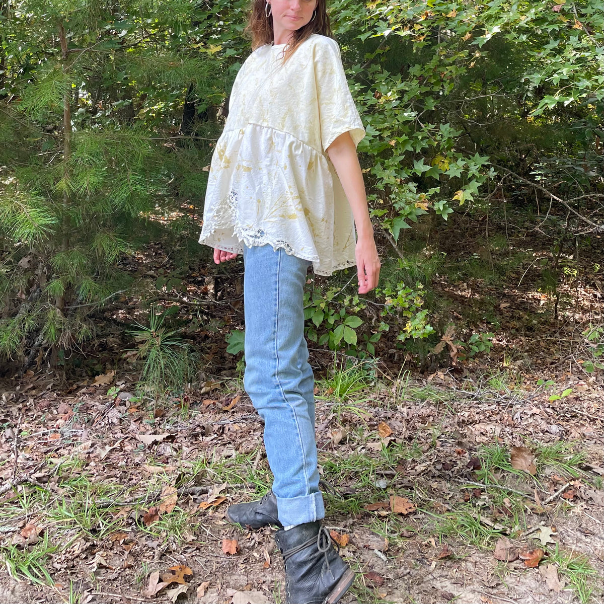A woman in jeans and boots standing in the woods.