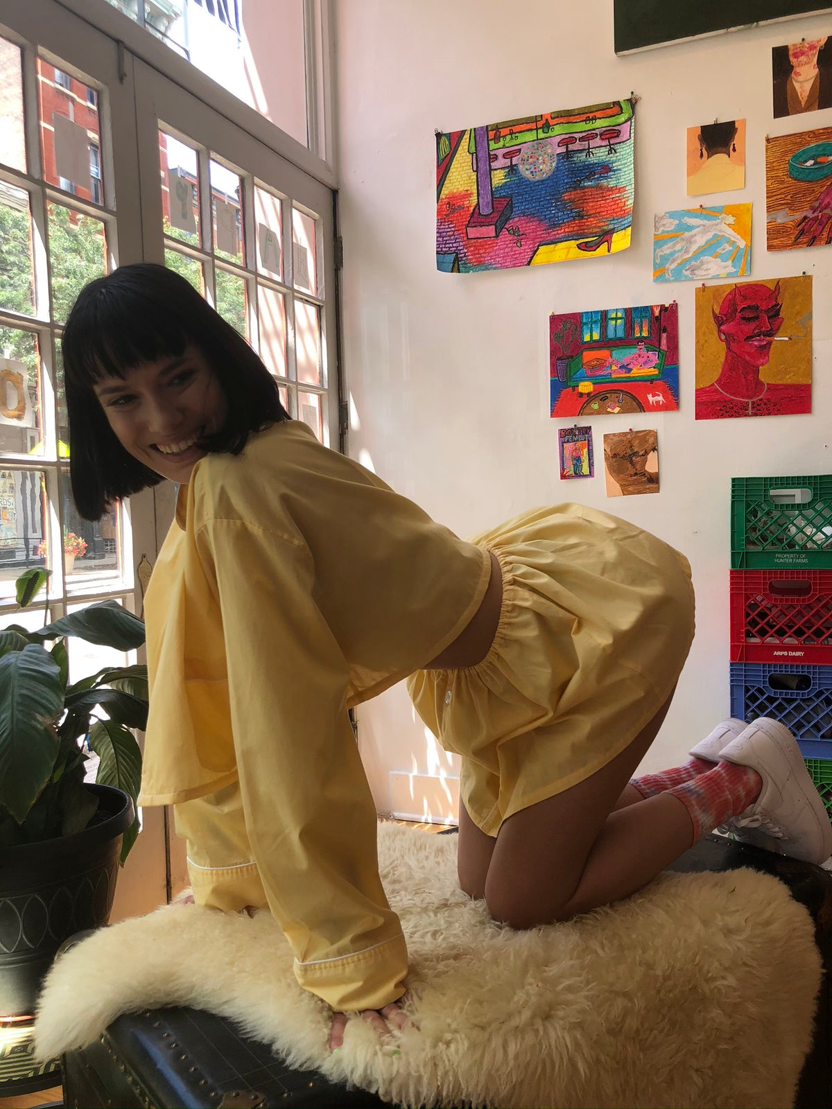 A woman in a yellow Blooming Marigold - 2pc set dress is sitting on a stool.