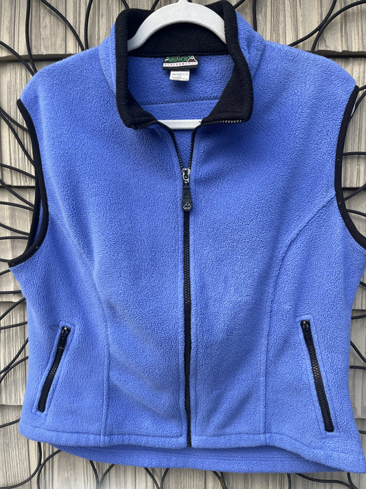 A women's blue flee vest hanging on a wall.