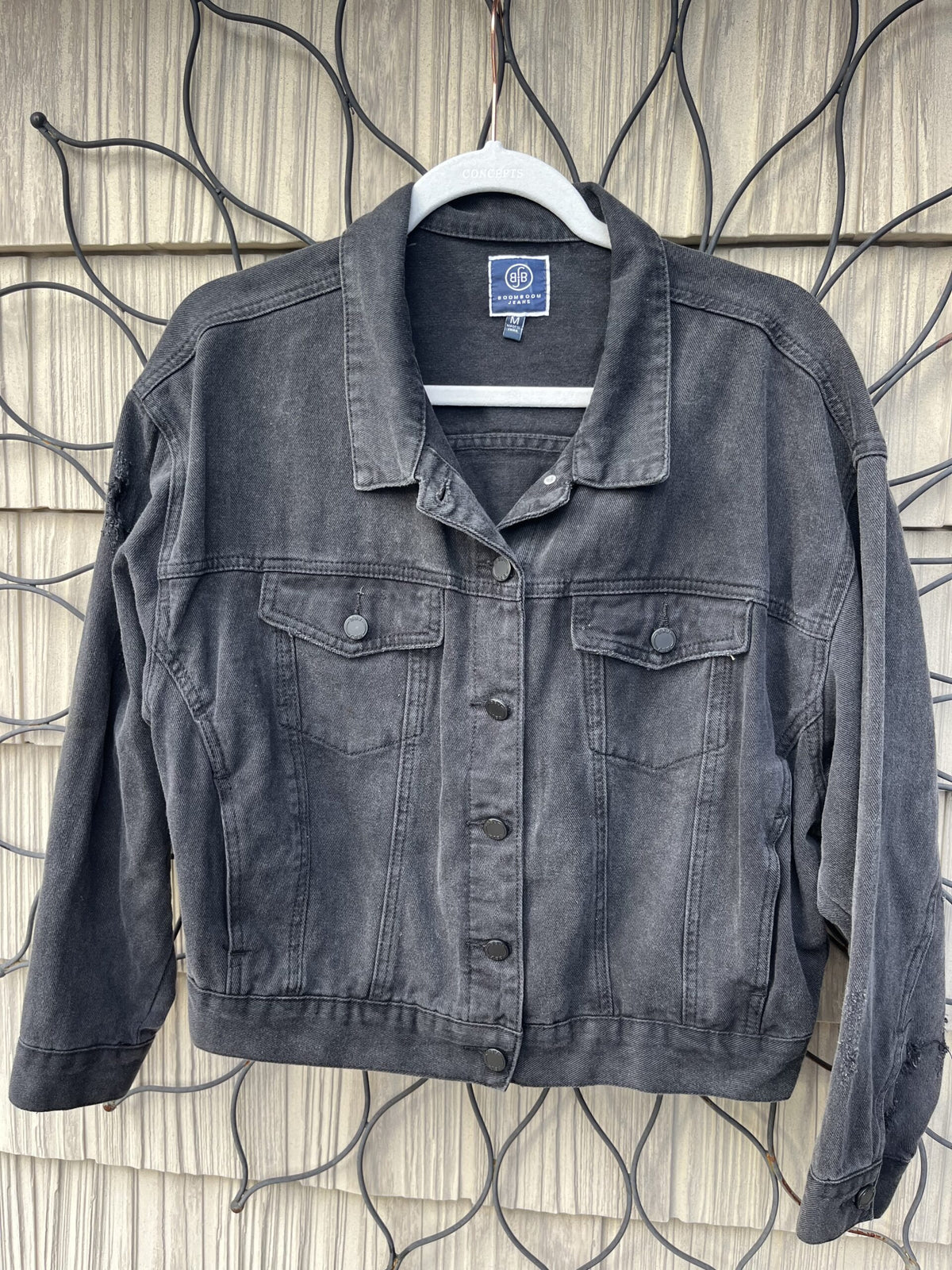 A black denim jacket hanging on a wall.