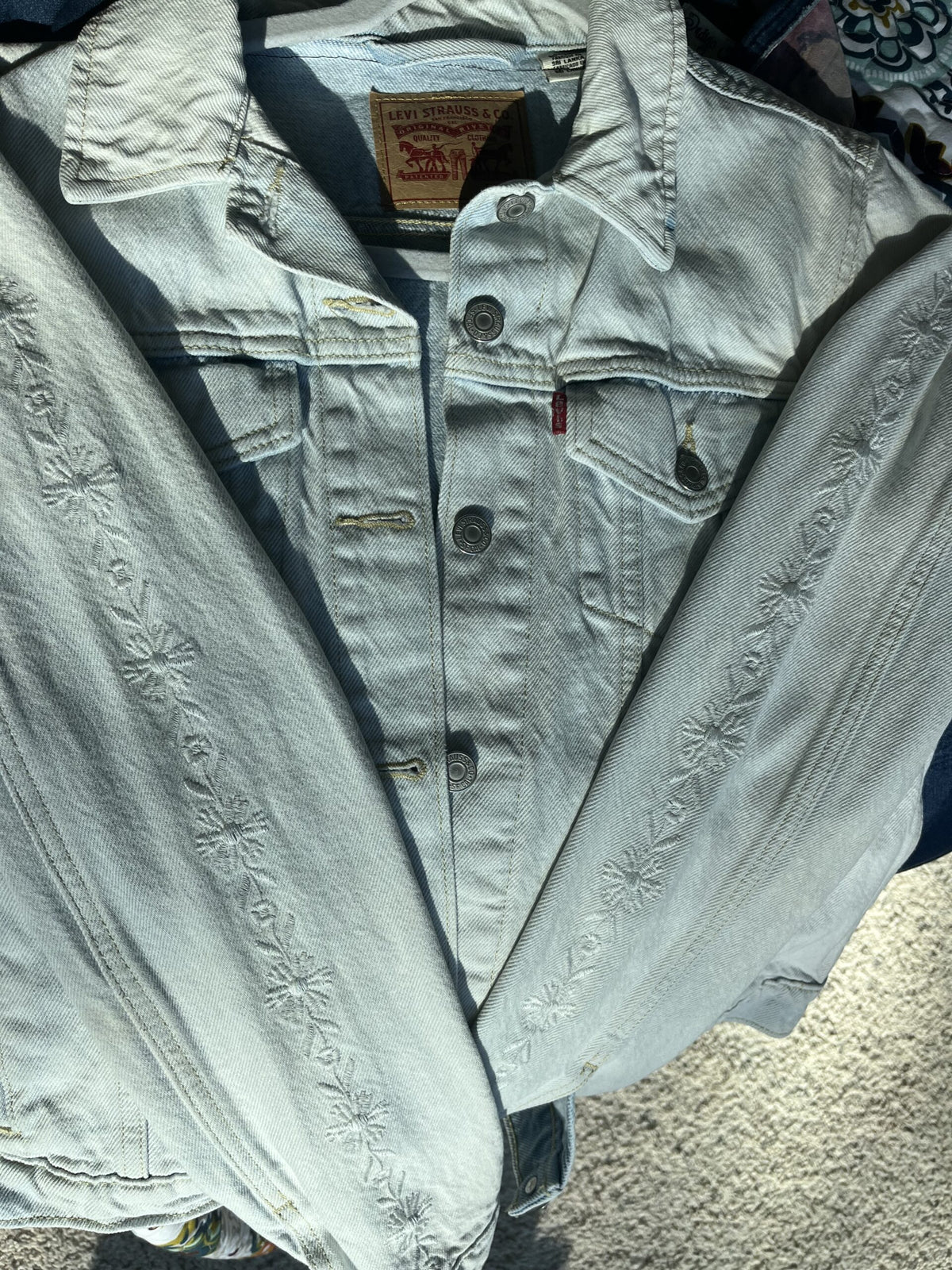 A levi's denim jacket is laying on the ground.