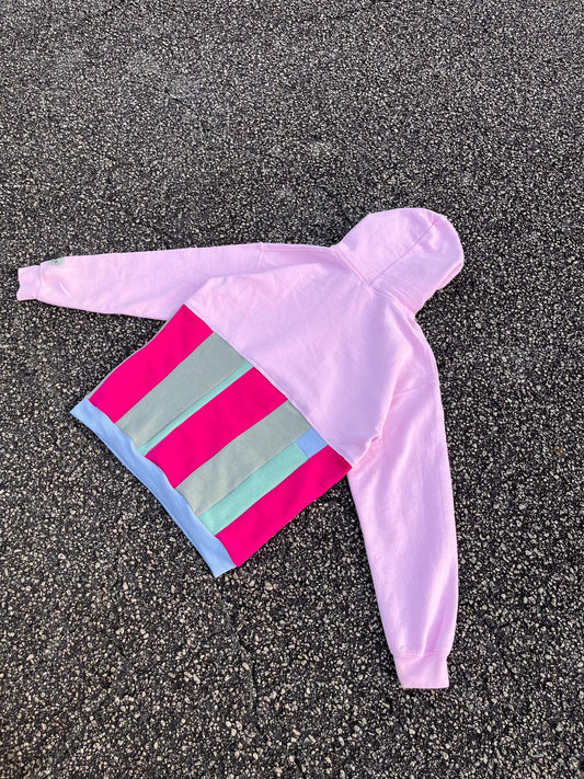 A pink and blue striped hoodie laying on the ground.