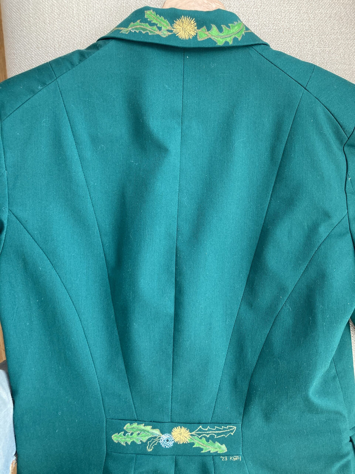 The back of a green jacket with flowers on it.