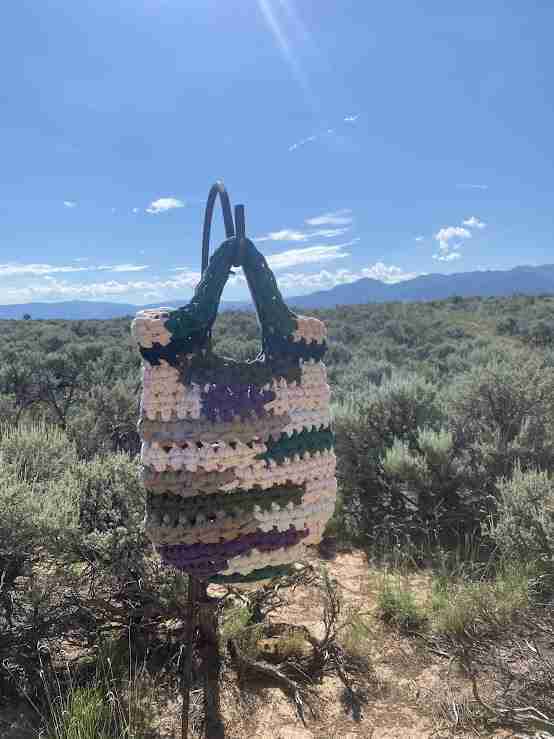 a crocheted bag sitting on top of a metal pole.