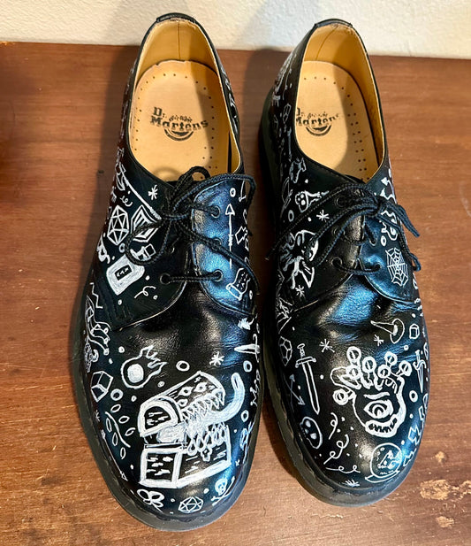A pair of black shoes with white drawings on them.