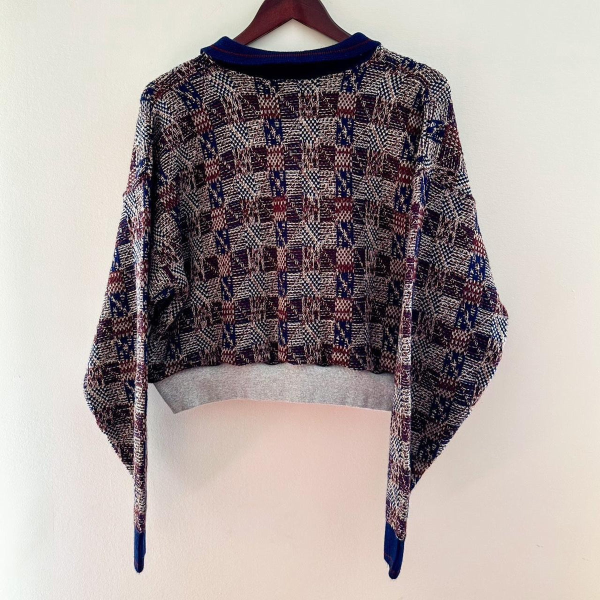 A sweater hanging on a hanger with a pattern on it.