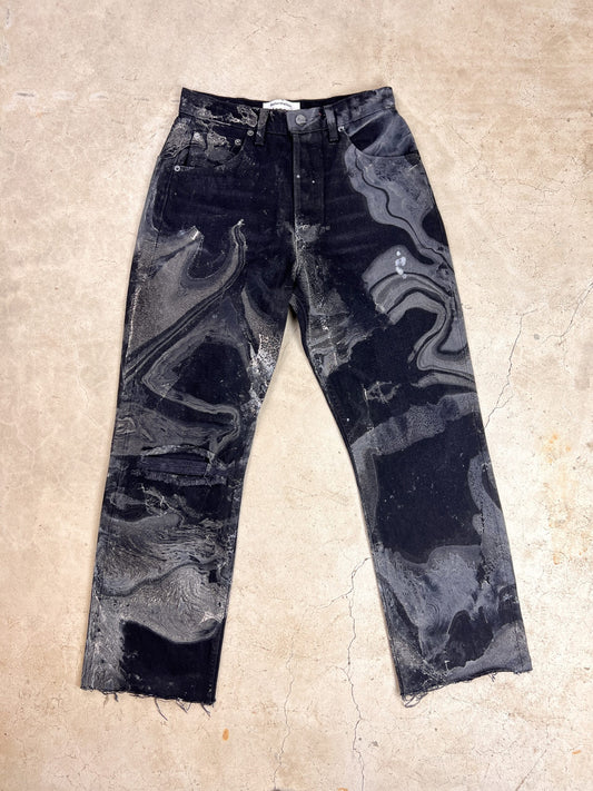 A pair of black jeans with stains on them.