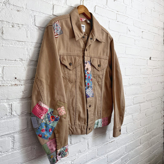 A patchwork denim jacket hanging on a brick wall.