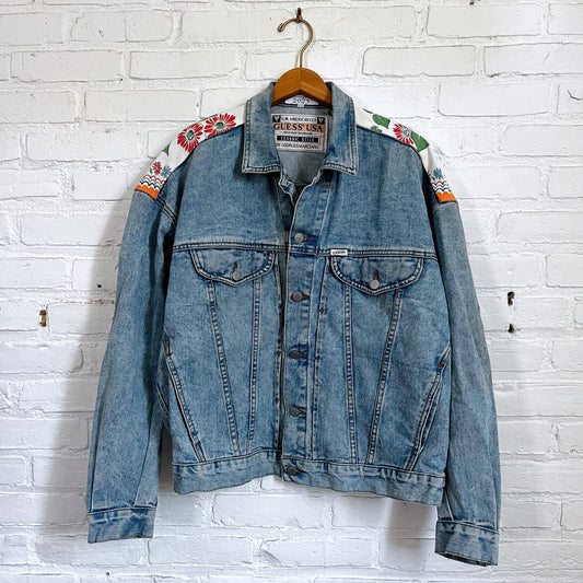 A denim jacket hanging on a brick wall.
