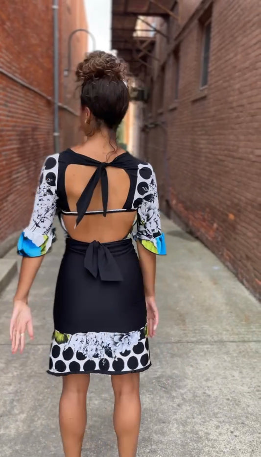 A woman walking down an alley in a black and white polka dot dress.