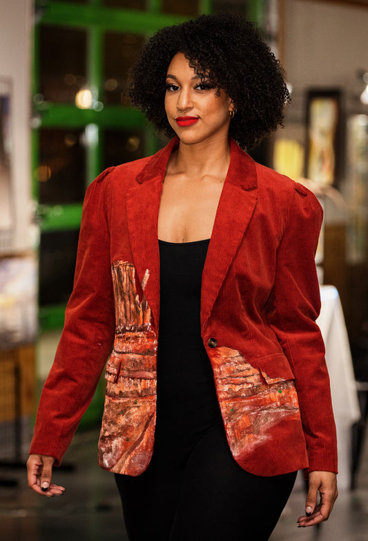 A woman wearing a red hand-painted blazer and black pants.
