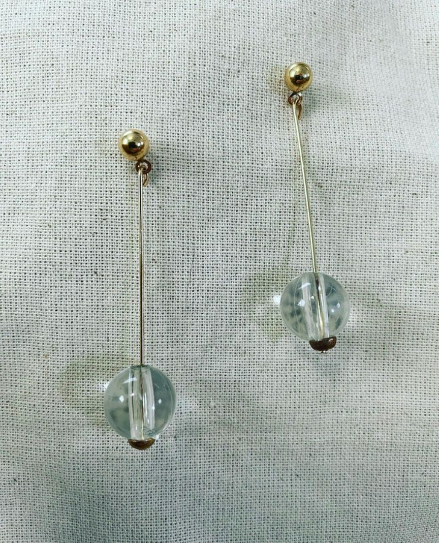 a pair of earrings on a white cloth.