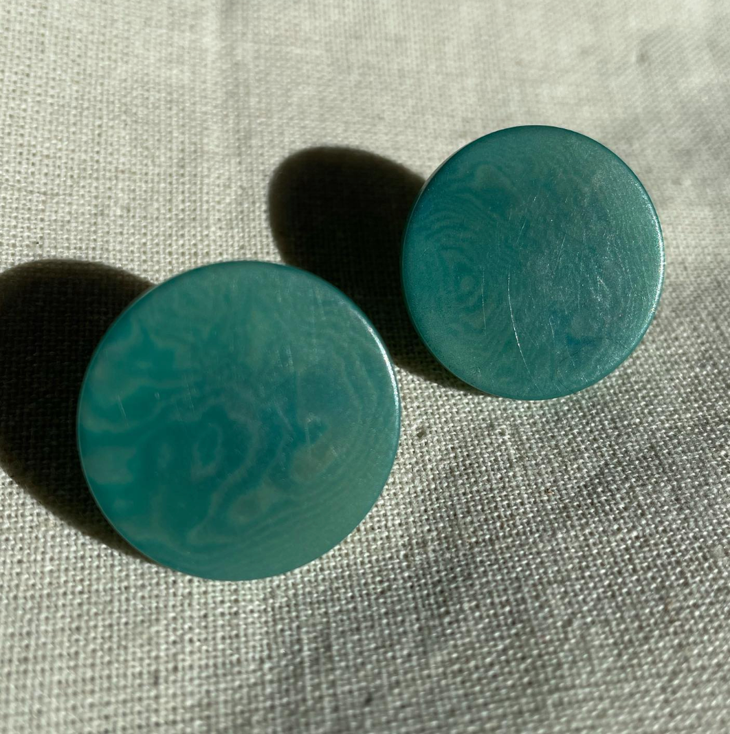 a pair of blue buttons sitting on top of a white cloth.