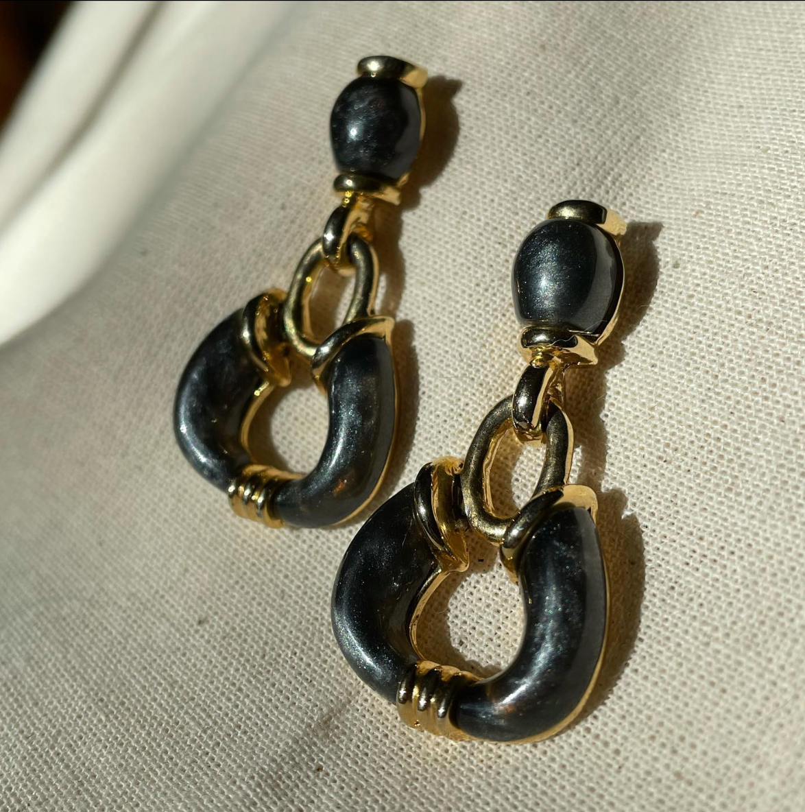 a pair of black and gold toned earrings.