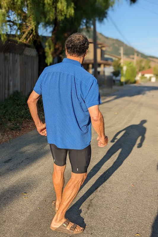 A man walking down a street in shorts and a shirt.