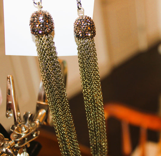 A pair of earrings with tassels hanging from them.