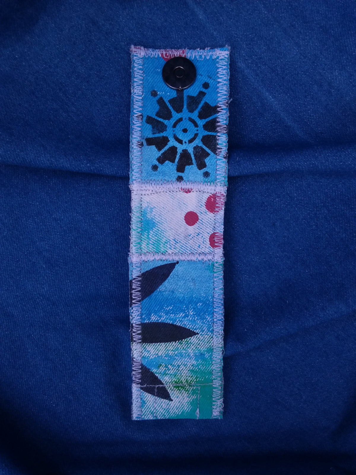 A painted cuff bracelet of recycled denim