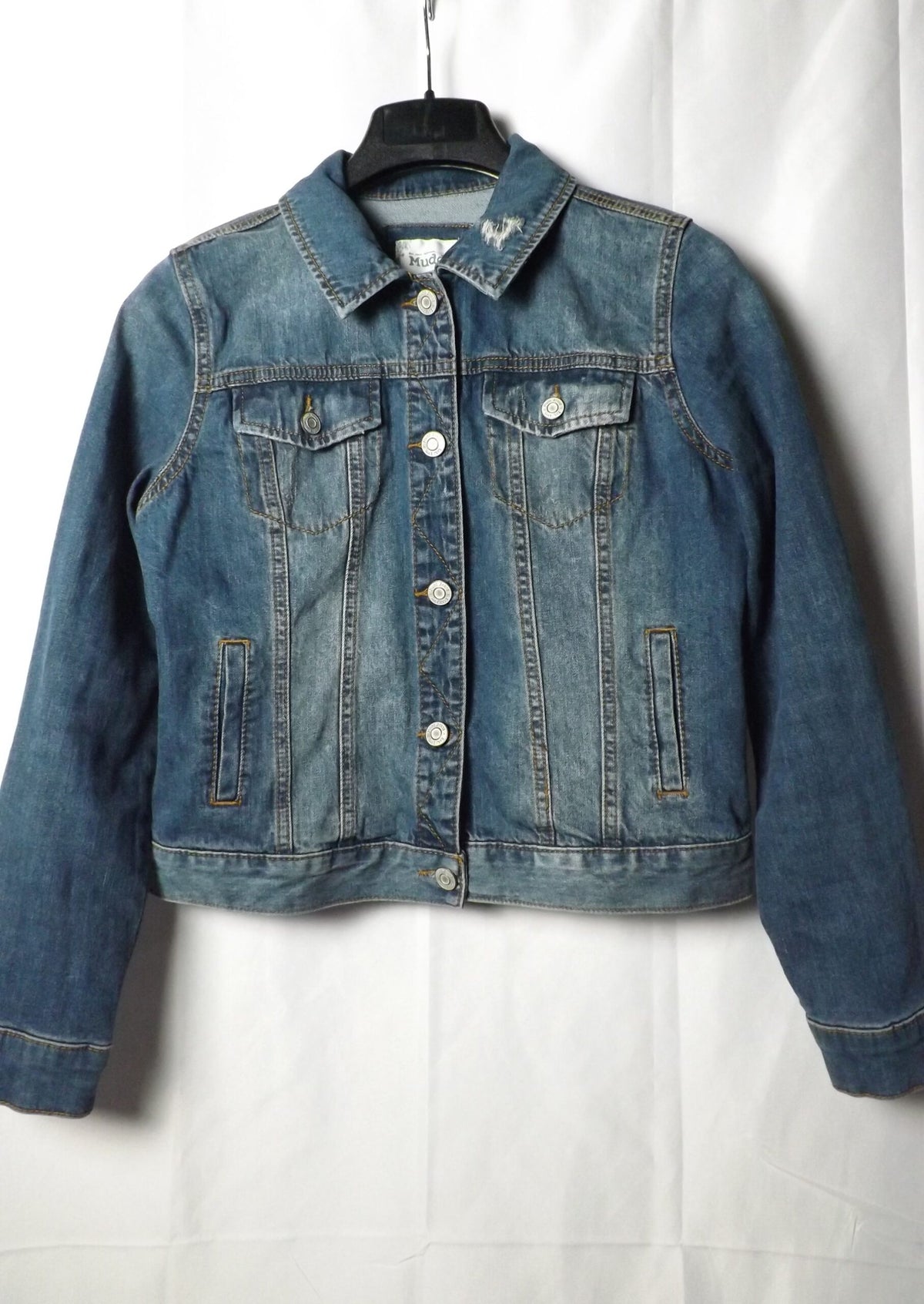 A distressed denim jacket on a hanger