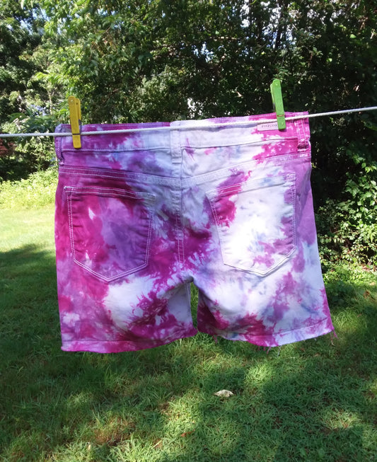 A pair of pink and purple tie dye shorts hanging on a clothes line.