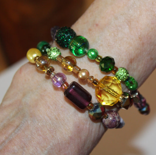 A woman wearing a bracelet with green, yellow, and purple beads.