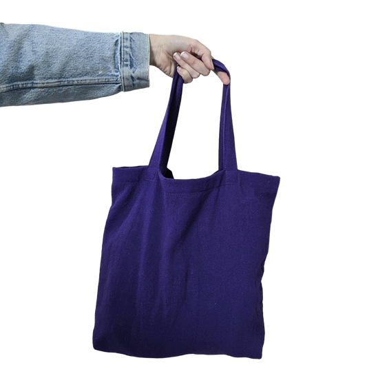 A person holding a purple tote bag on a black background.