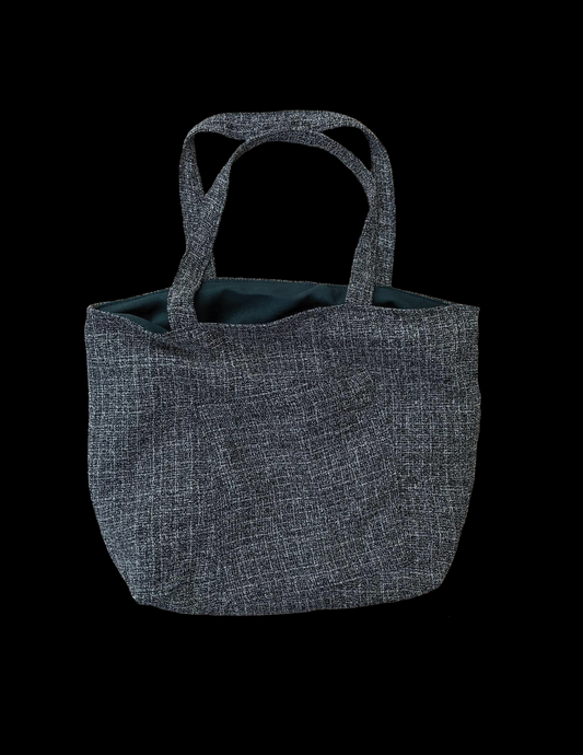 A grey tote bag on a black background.
