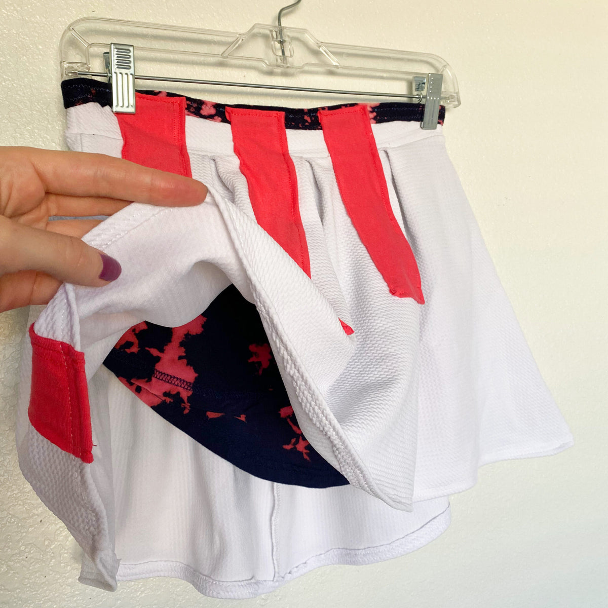 A hand holding a white and red shorts.