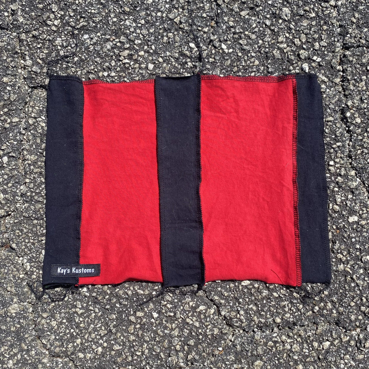 a red and black blanket laying on the ground.