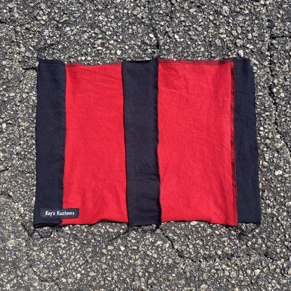 a red and black blanket laying on the ground.