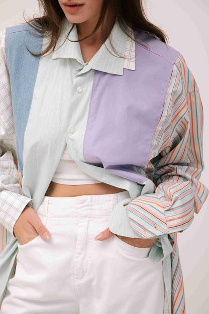 a woman wearing a colorful shirt and white pants.