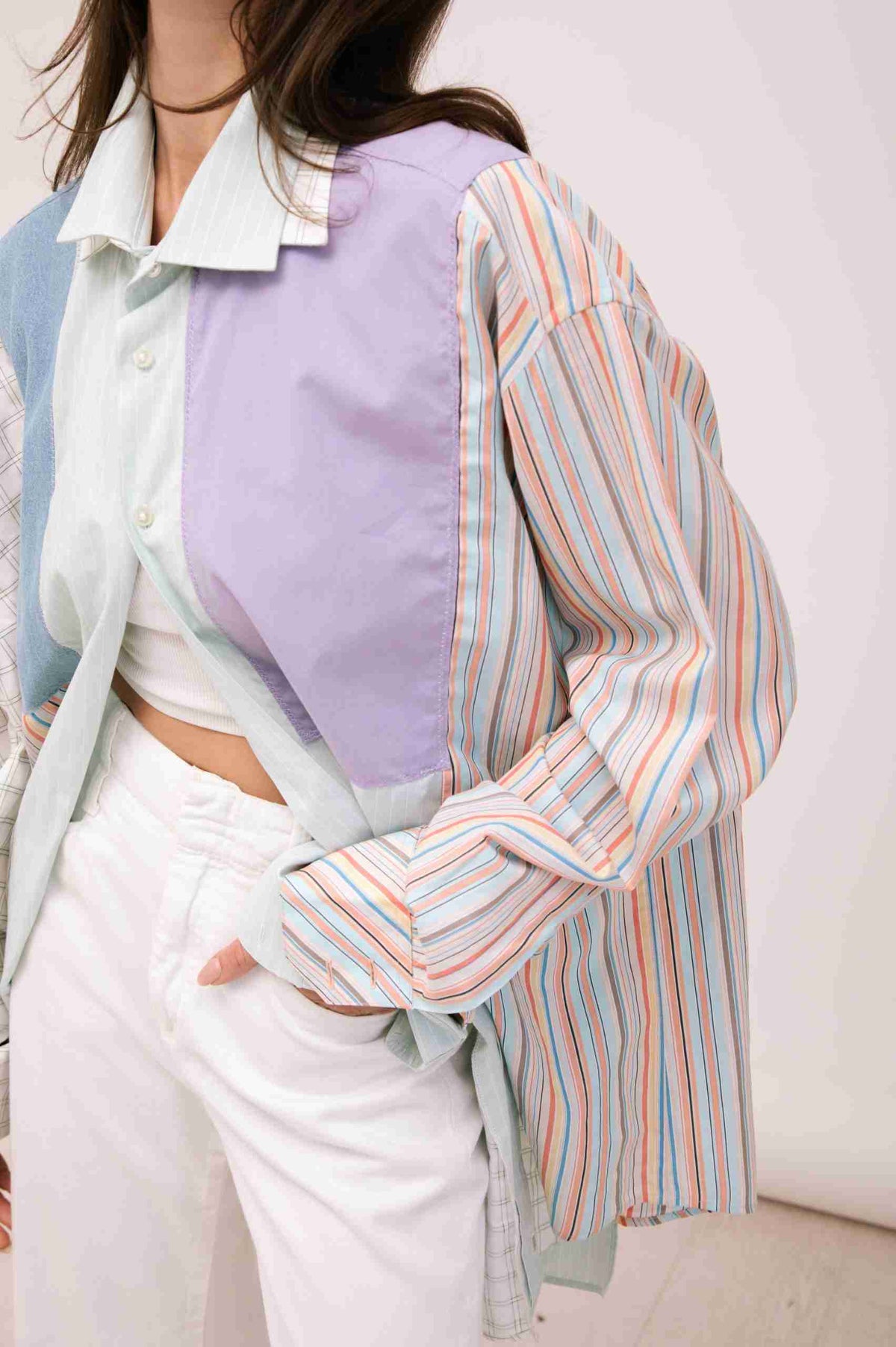 a woman wearing a colorful shirt and white pants.
