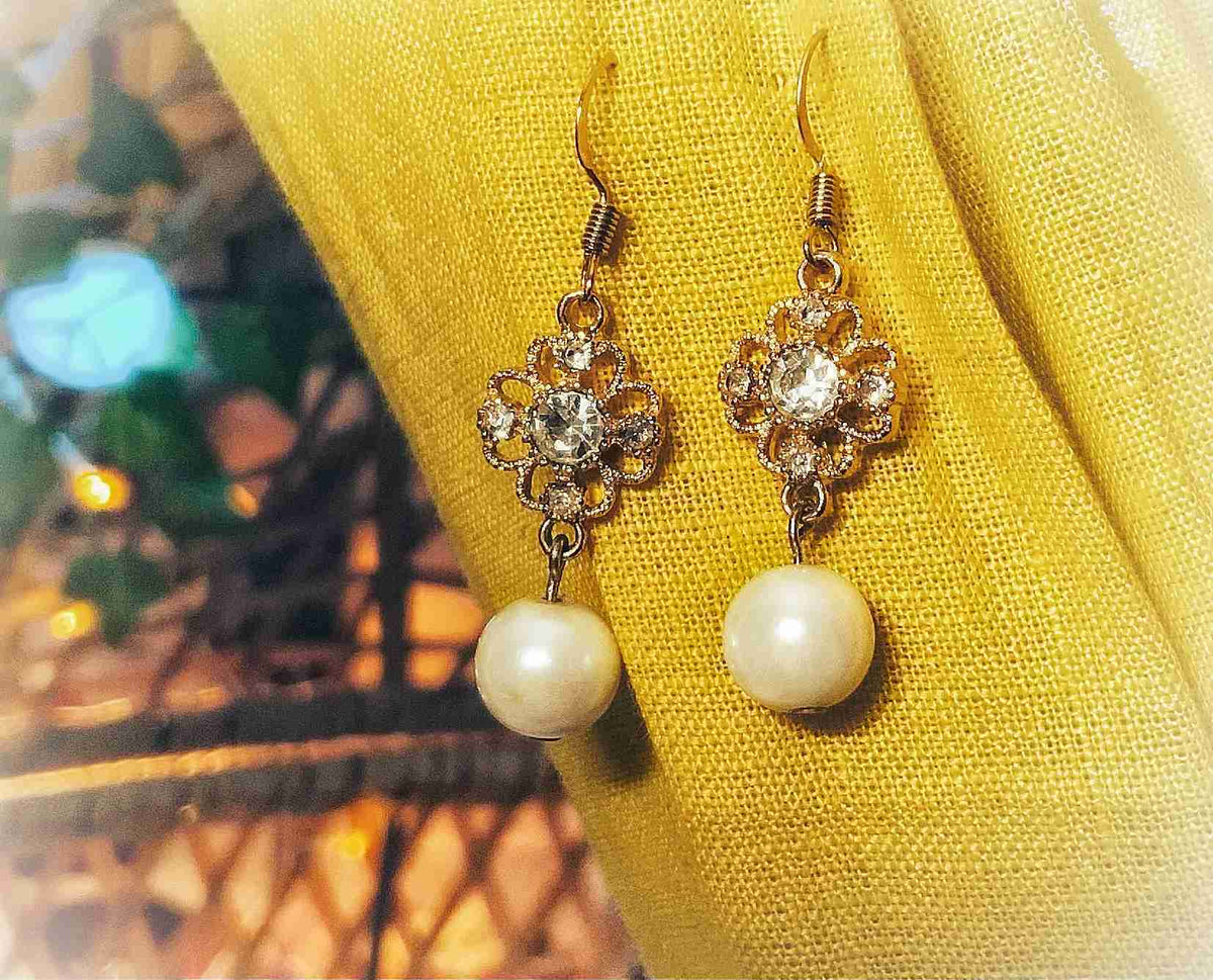 a pair of earrings sitting on top of a yellow cloth.