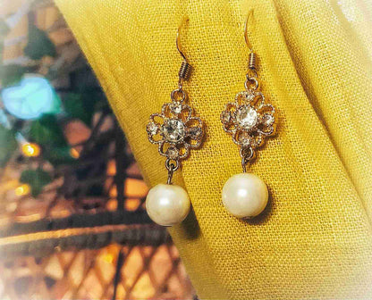 a pair of earrings sitting on top of a yellow cloth.