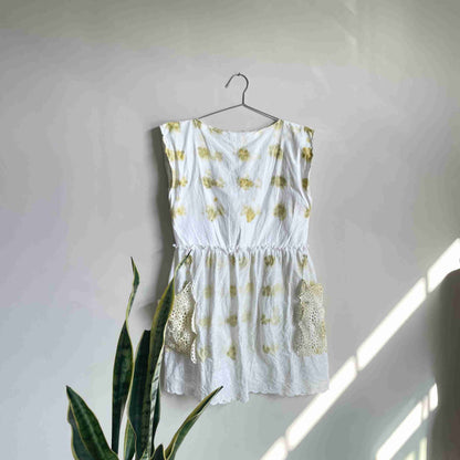 a white top hanging on a wall next to a potted plant.