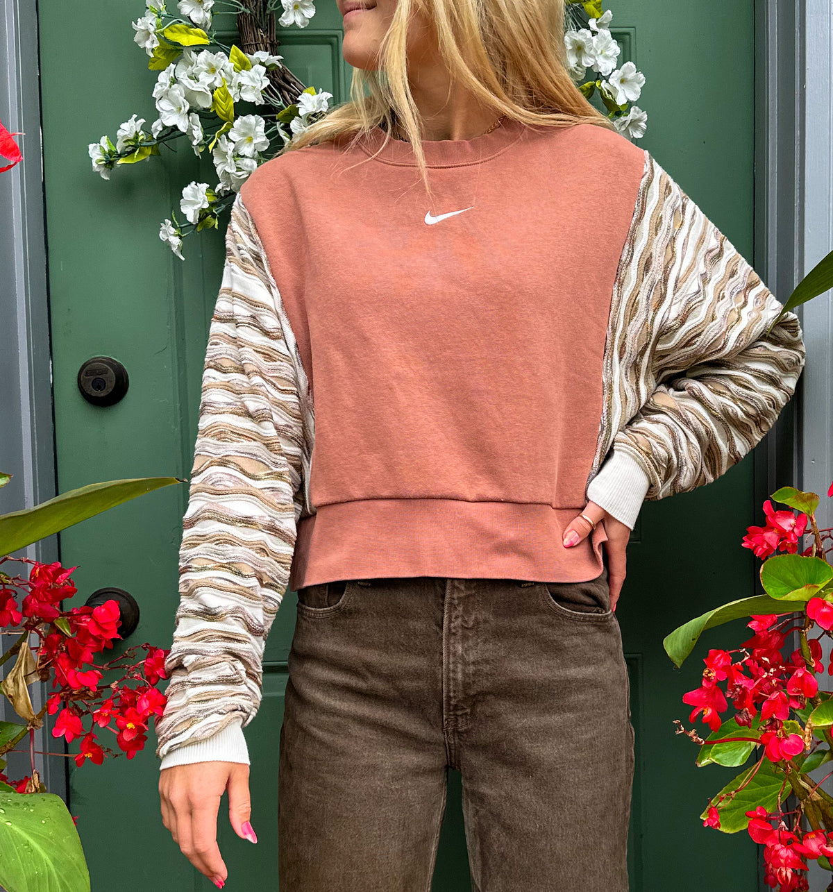 A woman wearing a nike cropped sweater and brown pants.